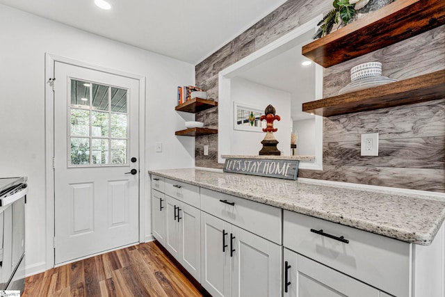 kitchen with light stone counters, light hardwood / wood-style flooring, electric range, white cabinets, and backsplash