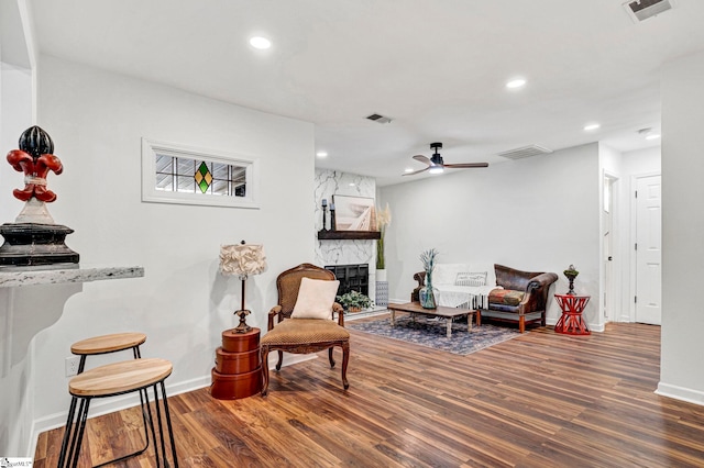 sitting room featuring a fireplace, dark hardwood / wood-style floors, and ceiling fan