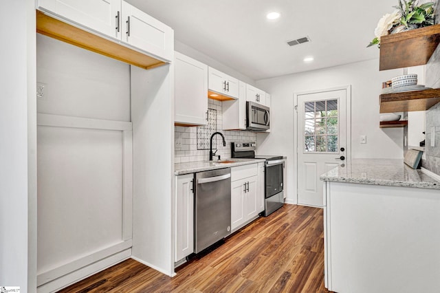 kitchen featuring sink, dark wood-type flooring, white cabinetry, stainless steel appliances, and light stone countertops