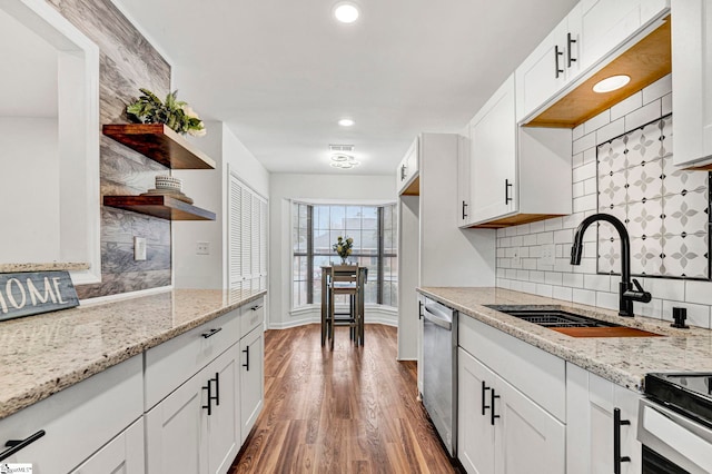 kitchen featuring dishwasher, wood-type flooring, sink, white cabinets, and light stone countertops