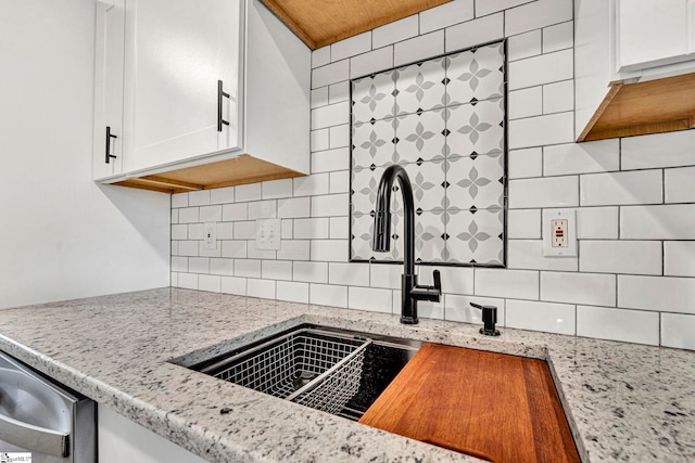 kitchen with light stone countertops, sink, decorative backsplash, and white cabinets