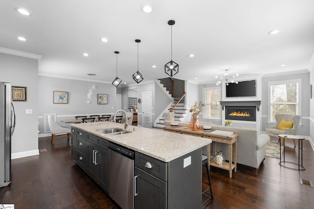 kitchen with sink, a breakfast bar area, appliances with stainless steel finishes, hanging light fixtures, and a center island with sink