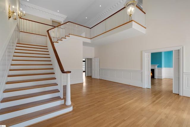 stairway with an inviting chandelier, wood-type flooring, and a high ceiling