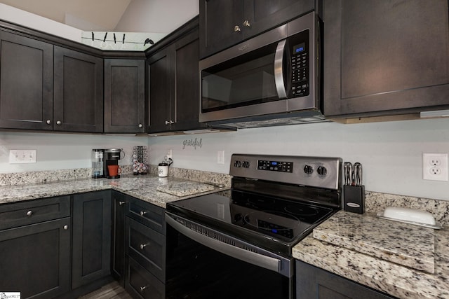 kitchen with dark brown cabinetry, appliances with stainless steel finishes, and light stone countertops