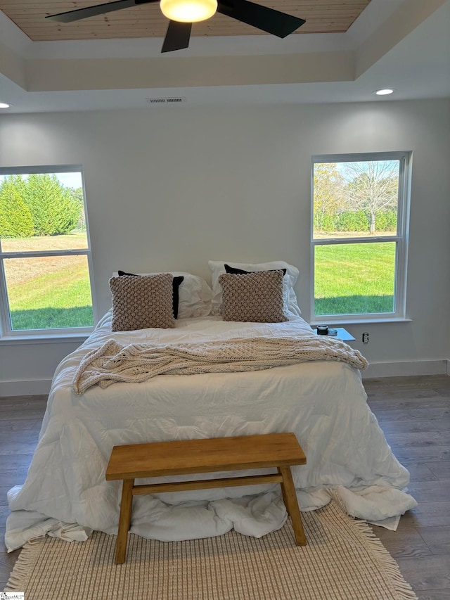 bedroom with a tray ceiling, dark wood-type flooring, and ceiling fan