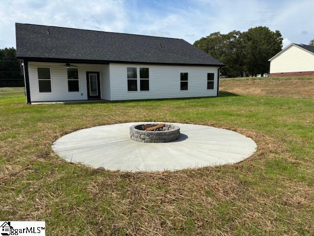 rear view of house featuring a yard, a patio area, and a fire pit