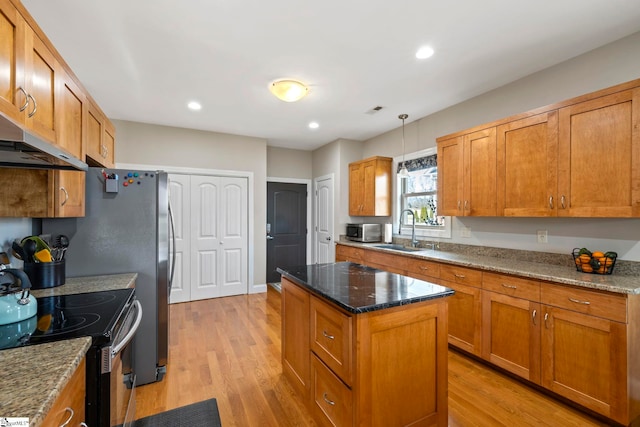 kitchen featuring stainless steel appliances, sink, a kitchen island, and stone counters