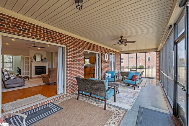 sunroom with ceiling fan and a fireplace