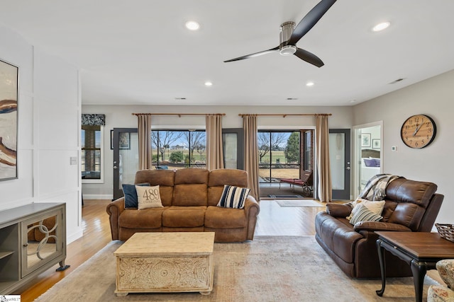 living room featuring a wealth of natural light, ceiling fan, and light hardwood / wood-style flooring