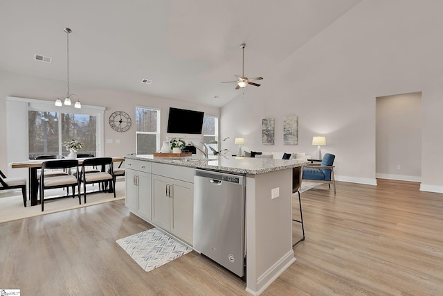 kitchen featuring white cabinetry, hanging light fixtures, a center island with sink, light hardwood / wood-style flooring, and stainless steel dishwasher