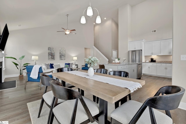 dining area with sink, light hardwood / wood-style floors, ceiling fan, and a high ceiling