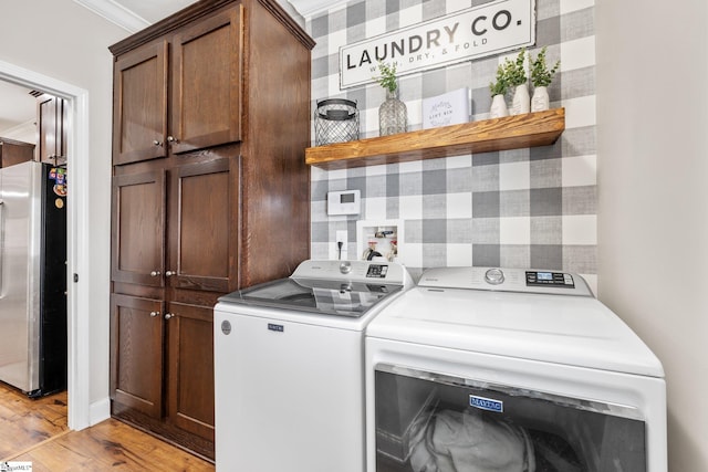 washroom with cabinets, crown molding, washer and dryer, and light hardwood / wood-style flooring