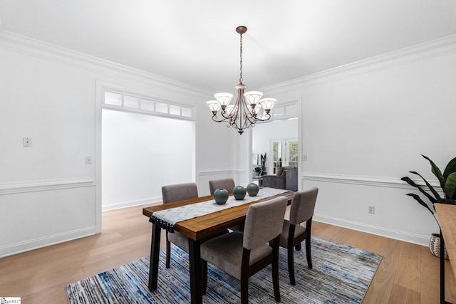 dining space with ornamental molding, hardwood / wood-style floors, and a notable chandelier