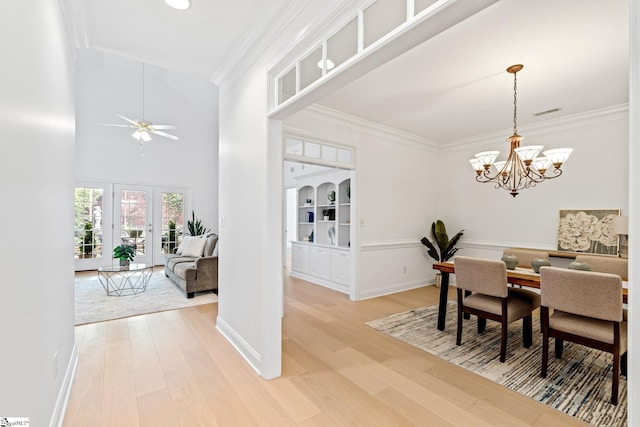 dining room featuring hardwood / wood-style flooring, a towering ceiling, ornamental molding, and ceiling fan with notable chandelier