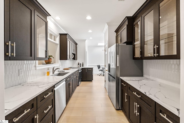 kitchen featuring sink, crown molding, appliances with stainless steel finishes, tasteful backsplash, and light stone countertops