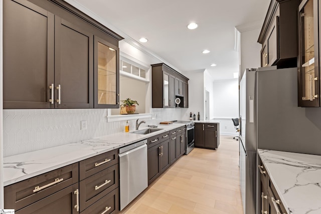 kitchen with light stone counters, appliances with stainless steel finishes, sink, and backsplash