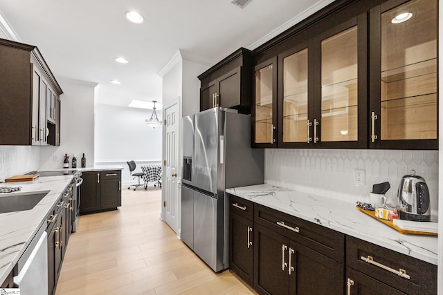 kitchen with pendant lighting, light stone counters, light hardwood / wood-style floors, stainless steel appliances, and crown molding