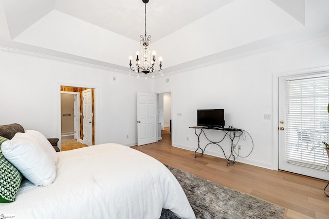 bedroom featuring multiple windows, access to exterior, light hardwood / wood-style flooring, and a raised ceiling