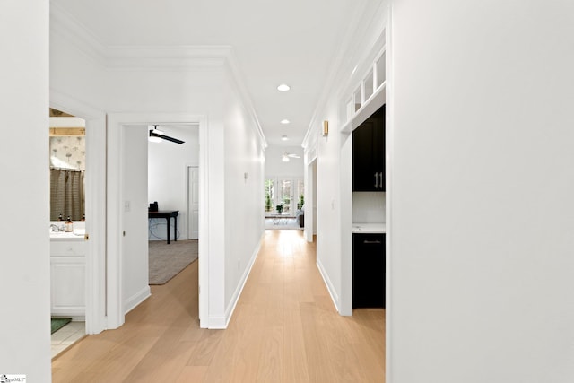 hall with ornamental molding and light hardwood / wood-style floors