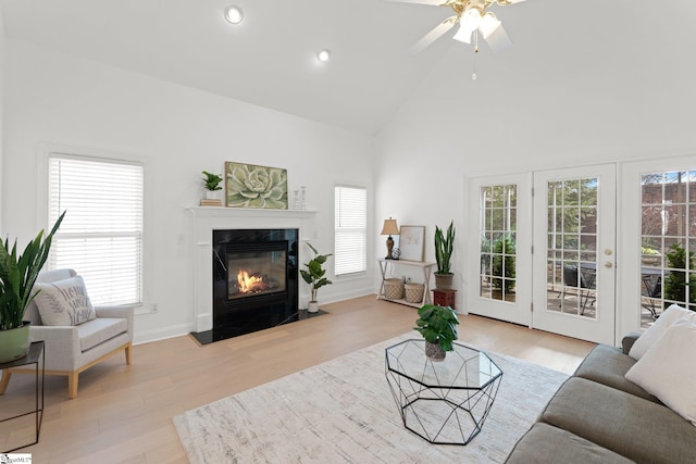 living room featuring plenty of natural light, high vaulted ceiling, a high end fireplace, and light hardwood / wood-style floors