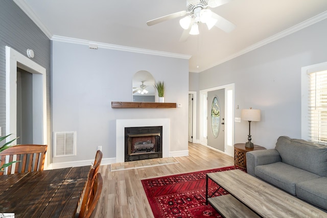 living room with wood-type flooring, ornamental molding, and ceiling fan