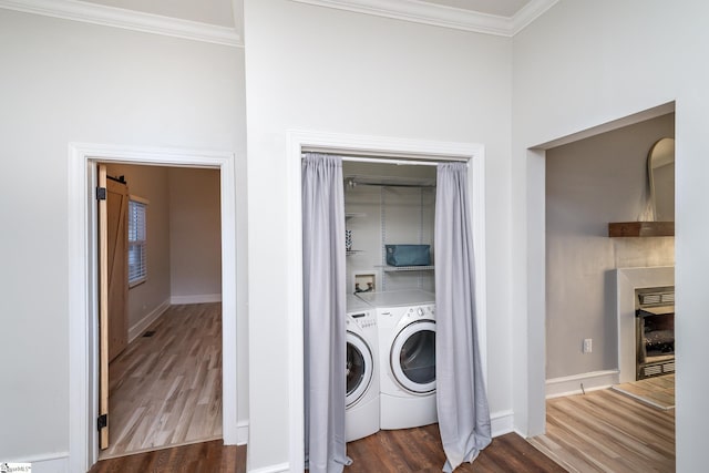 laundry room with crown molding, washer and dryer, and dark hardwood / wood-style floors