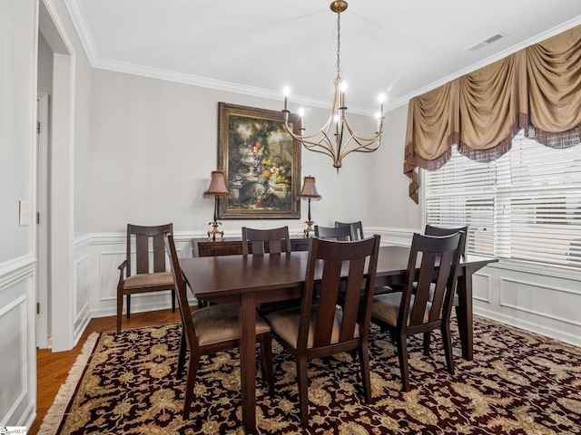 dining room with hardwood / wood-style flooring, crown molding, and an inviting chandelier