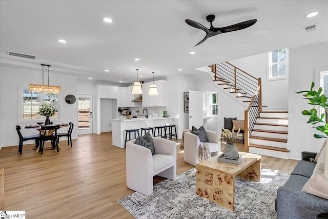 living room with ceiling fan, sink, and light wood-type flooring