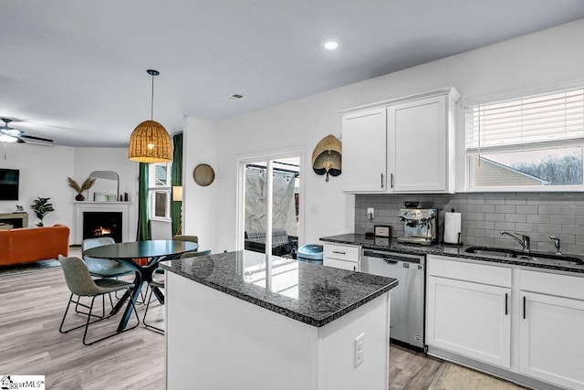 kitchen featuring a center island, dishwasher, sink, and white cabinets