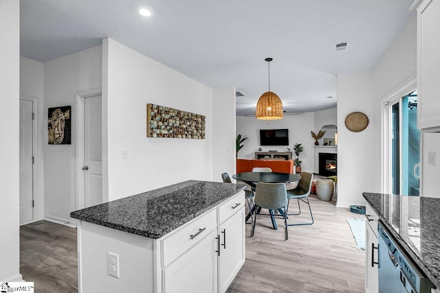 kitchen featuring decorative light fixtures, white cabinets, light wood-type flooring, and dark stone counters