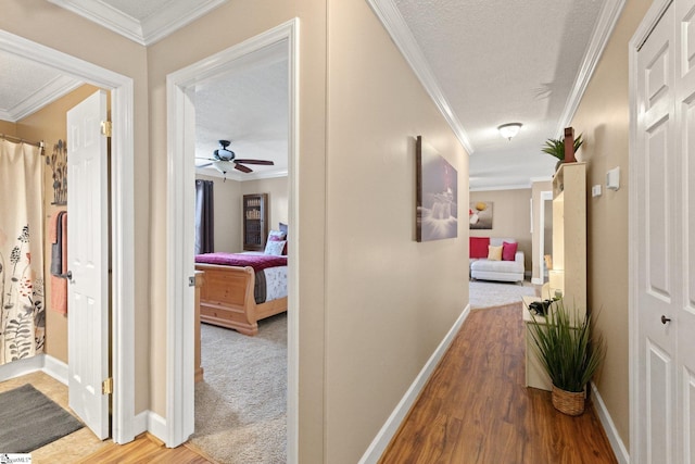 corridor with hardwood / wood-style flooring, crown molding, and a textured ceiling