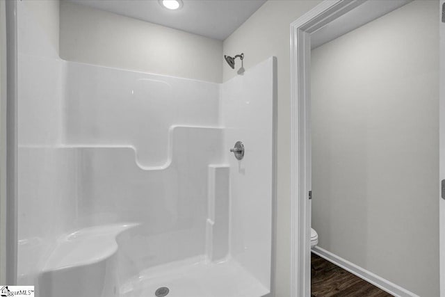 bathroom with walk in shower, hardwood / wood-style floors, and toilet