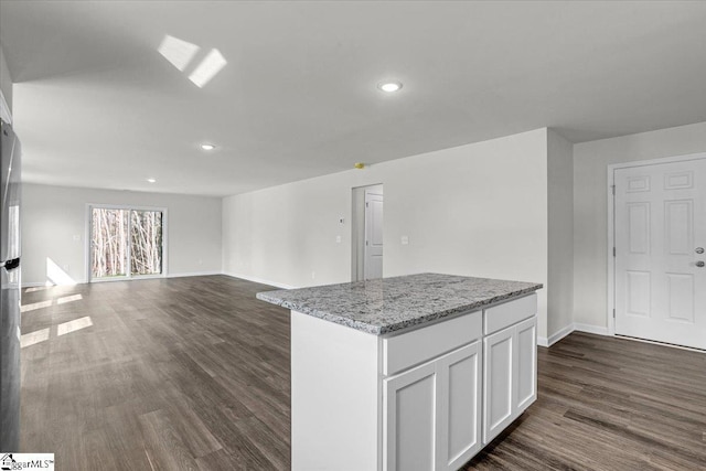 kitchen featuring light stone counters, dark wood-type flooring, a center island, and white cabinets