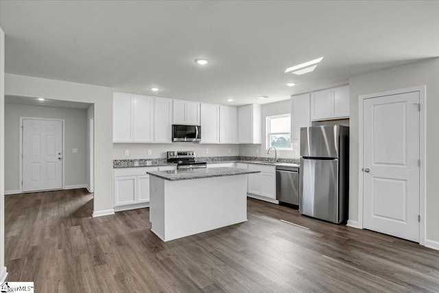 kitchen with light stone countertops, white cabinetry, appliances with stainless steel finishes, and a center island