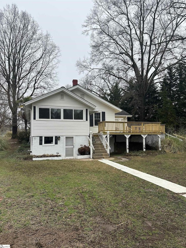 view of front facade with a wooden deck and a front lawn