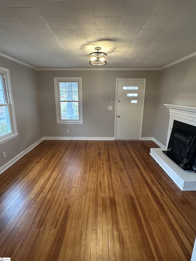 unfurnished living room featuring a fireplace, crown molding, and wood-type flooring