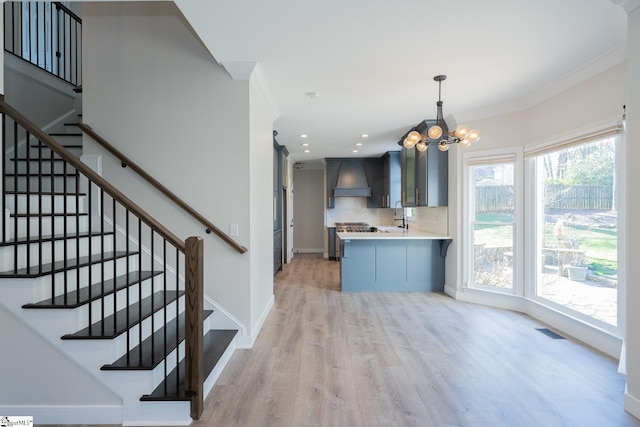 kitchen with premium range hood, decorative light fixtures, backsplash, kitchen peninsula, and crown molding