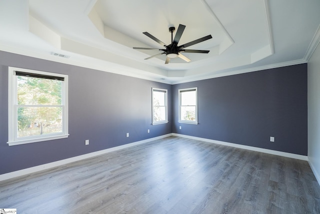 empty room featuring crown molding, hardwood / wood-style flooring, a raised ceiling, and ceiling fan