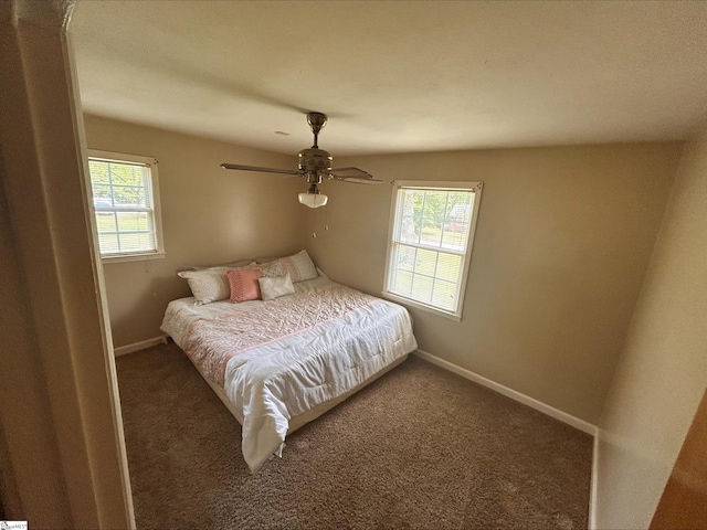 bedroom featuring multiple windows, ceiling fan, and dark colored carpet