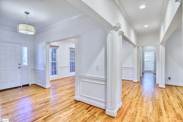 entrance foyer with ornamental molding, decorative columns, and light wood-type flooring