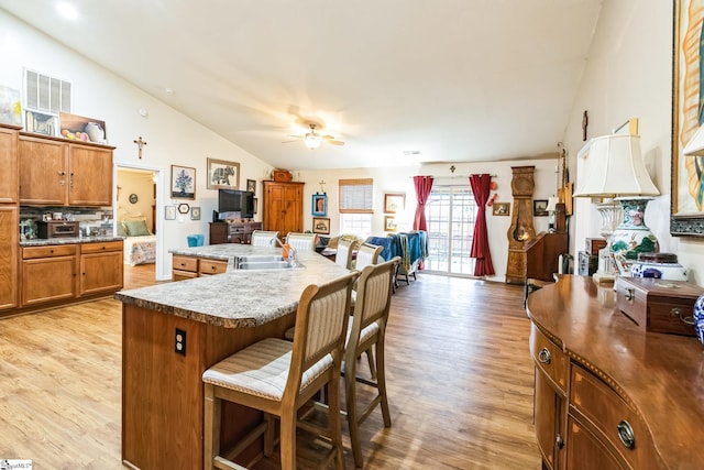 kitchen with lofted ceiling, a breakfast bar, sink, a kitchen island, and light hardwood / wood-style floors