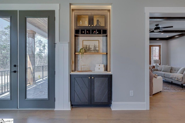 interior space with french doors, built in shelves, light wood-type flooring, ceiling fan, and beam ceiling