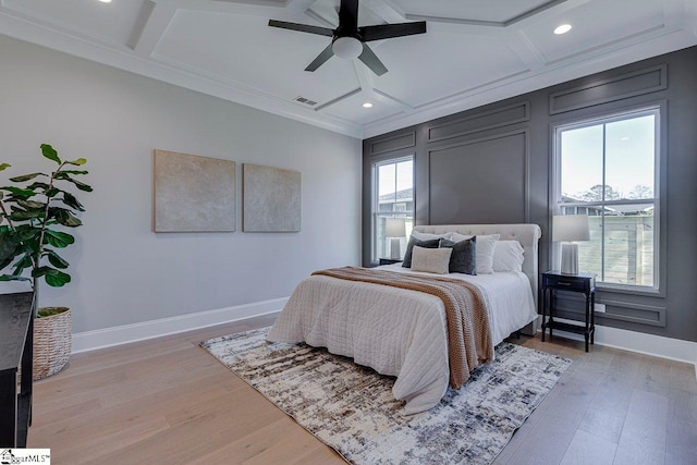 bedroom with beamed ceiling, ornamental molding, coffered ceiling, ceiling fan, and light wood-type flooring