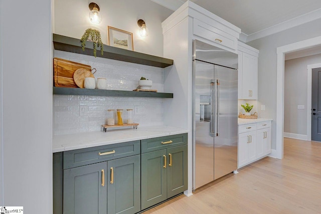 kitchen featuring light stone counters, built in fridge, light hardwood / wood-style floors, decorative backsplash, and white cabinets