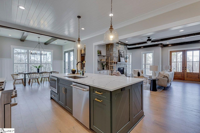 kitchen with french doors, gray cabinetry, decorative light fixtures, stainless steel appliances, and a kitchen island with sink