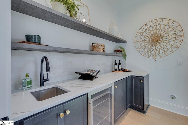 bar with wine cooler, light stone countertops, sink, and backsplash