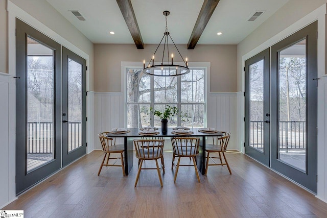 dining area with hardwood / wood-style floors, beam ceiling, and french doors