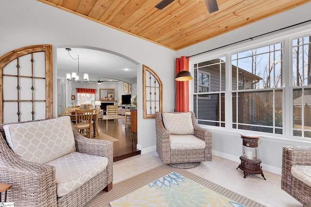 living area featuring light tile patterned flooring, a healthy amount of sunlight, ceiling fan with notable chandelier, and wooden ceiling