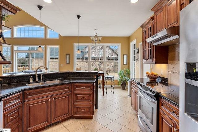 kitchen featuring sink, dark stone countertops, stainless steel appliances, light tile patterned flooring, and decorative light fixtures