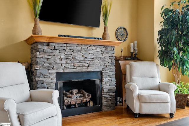 living area featuring a stone fireplace and wood-type flooring